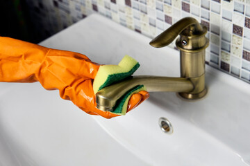 Improper care of brass water faucet, housekeeper wipes tap with abrasive side of washing sponge.