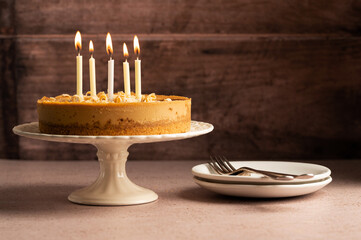 Birthday cake with burning candles, rustic wooden background, copy space.