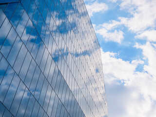 Fototapeta na wymiar The sky with white clouds reflecting in the glass windows of a modern office building.