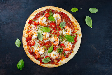 Traditionelle italienische Pizza frutti di mare Riesengarnelen, Tomaten und Mozzarella serviert als Draufsicht auf einem rustikalen schwarzen Board mit Textfreiraum 