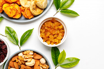 Dried fruits and nuts, branch with young green leaves on white background . Concept of the Jewish holiday Tu Bishvat. Copy space