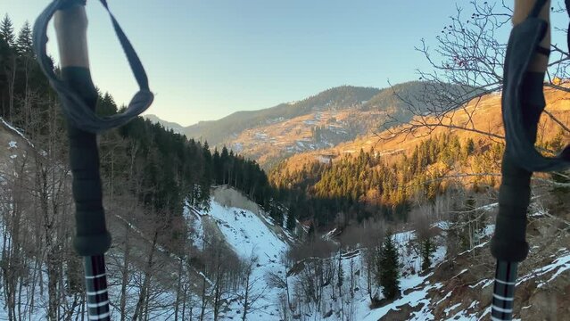 Zoom in landscape panorama hiking poles on hiking trail with panorama of snowy caucasus mountains in bright warm spring evening during sunset. Snow melts springtime arrive