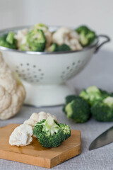 Fresh green broccoli and cauliflower on a wooden chopping board on a linen tablecloth. Broccoli cabbage leaves. Light background. Vegetarian food. Healthy lifestyle.
