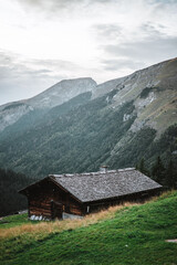 Fototapeta na wymiar Wooden hut in the alps with mountains in the background Panorama