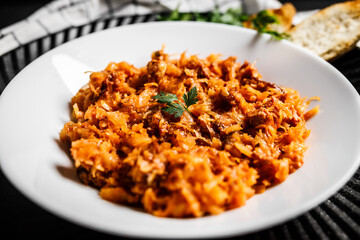 Traditional Polish kraut stew bigos with sausage, meat on black table