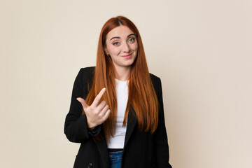 Young business caucasian redhair woman pointing with finger at you as if inviting come closer.