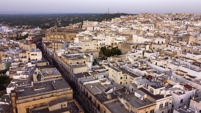 Aerial drone footage of Ostuni - La Citta Bianca (white city), Puglia, Italy at sunset. Establish scene of main street to medieval historic old town, landmark tourist destination from above