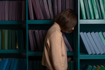 Exam stress, tired girl on the background of bookshelves. Natural sciences. A large amount of...