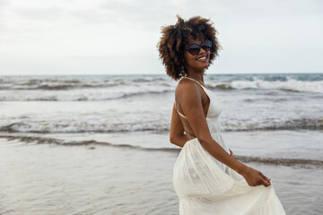 Fototapeta na wymiar Portrait of beautiful young African woman smiling happily with white dress and beach background.