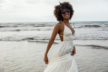 Fototapeta na wymiar Portrait of beautiful young African woman smiling happily with white dress and beach background.