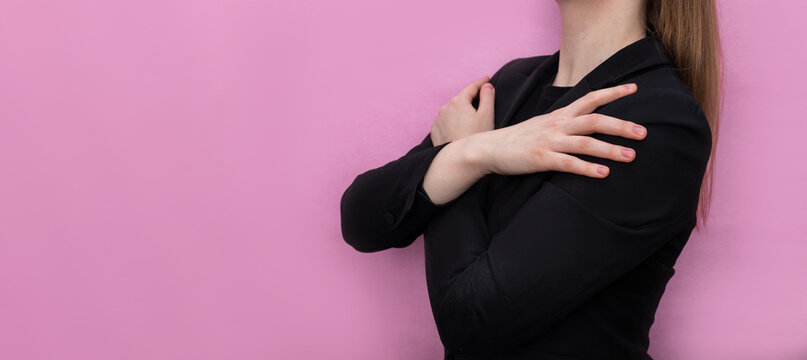The girl hugs herself on a pink background. Concept for March 8th, #IWD2023, #EmbraceEquity, International Women's Day.	