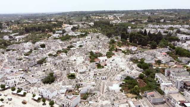Aerial drone footage of Alberobello, Puglia, Italy. Establish scene of the traditional whitewashed, conical roof (trulli) UNESCO world heritage site, landmark tourist destination from above.