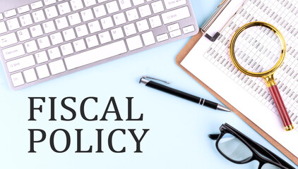 FISCAL POLICY text on blue background with keyboard and clipboard, business concept