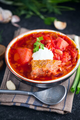 Ukrainian borscht with white beans on the bowl. Plate of red beet root soup borsch on black rustic table. Beetroot soup Top view. Traditional Ukraine food cuisine. Vertical shot