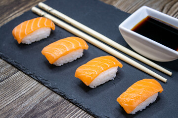 Salmon sushi with soy sauce on a slate base