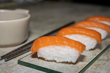Salmon sushi with soy sauce on a glass base