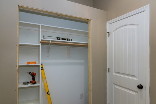 Installation of an interior white melamine shelf to be used to store clothing, with many empty shelves accommodate clothing
