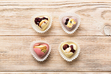 chocolate sweets in the form of a heart with fruits and nuts on a colored background. top view with space for text, holiday concept