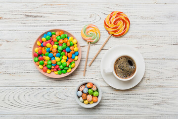 Coffee cup with chocolates and colored candy. Top view on table background with copy space