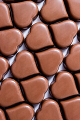 Chocolate candy hearts pattern extremely close up. Sweet Valentine's day concept. Selective soft focus, vertical banner