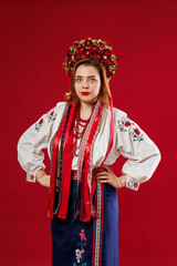 Portrait of ukrainian woman in traditional ethnic clothing and floral red wreath on viva magenta studio background. Ukrainian national embroidered dress call vyshyvanka. Pray for Ukraine