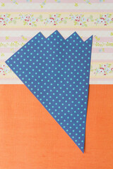 blue paper triangle with spots on orange and pink paper with stripes