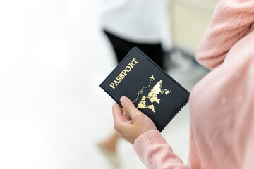 Asian woman holding passport and luggage with using mobile phone walking to airline check in counter in airport terminal. People travel on holiday vacation and global airplane transportation concept.