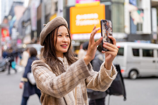 Asian woman friends using mobile phone taking selfie while travel and shopping at Shibuya, Tokyo, Japan. Attractive girl enjoy and fun outdoor lifestyle travel city street on autumn holiday vacation.