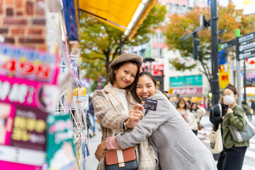 Happy Asian woman friends shopping with using credit card making payment at Shibuya, Tokyo, Japan...