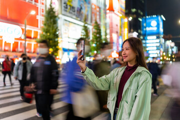 Asian woman using mobile phone taking selfie during travel and shopping at Shibuya, Tokyo, Japan...