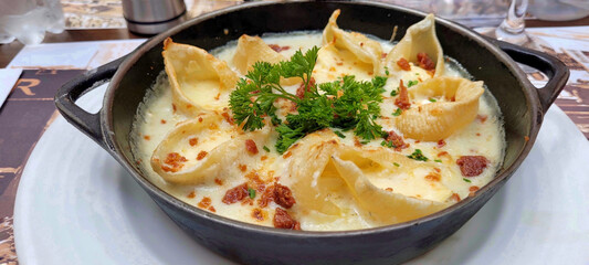 Baked conchiglioni pasta shells stuffed with brie cheese, four cheese salce and parma ham crispy with parmesan gratin.
