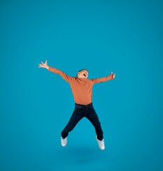 Overjoyed Little Boy Jumping In Air Over Blue Studio Background