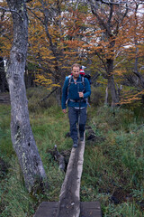 Naklejka premium white man crossing wooden bridge in the forest