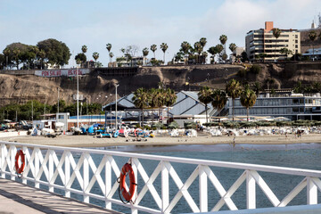 Chorillos Peru-June 2017-Artisanal fishing port with wooden pier and railing the Pacific Ocean, in the background modern buildings