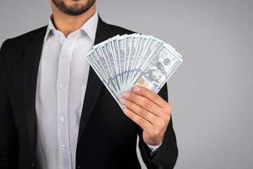 Unrecognizable businessman wearing suit holding dollar cash in hand