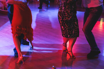 Couples dancing traditional latin argentinian dance milonga in the ballroom on a festival, tango studio, salsa, bachata and kizomba lesson in the red and purple lights, rehearsal in the dance class