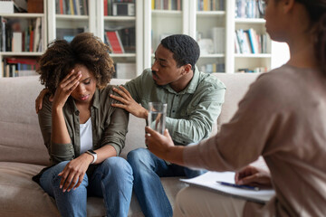 Loving black man comforting crying wife while having family therapy