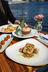 Woman eating Chilean Seabass dish on riverside during daytime