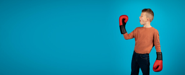 Emotional Boy Wearing Boxing Gloves Looking Aside At Copy Space
