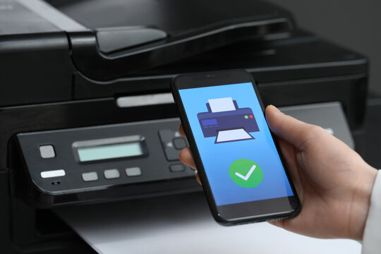 Man using printer management application on mobile phone indoors, closeup