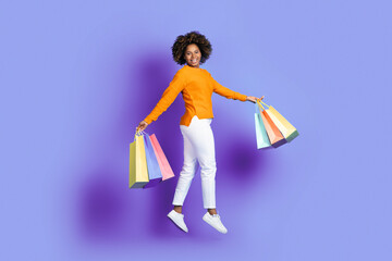 Emotional young african american woman jumping with shopping bags