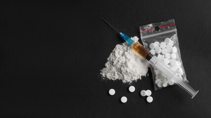 Powder, syringe and pills on black background, flat lay with space for text. Hard drugs