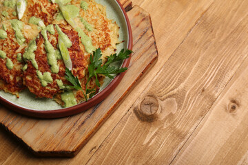 Tasty parsnip cutlets with sauce on wooden table, above view. Space for text