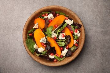 Delicious persimmon salad with cheese and pomegranate on grey table, top view