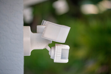 Motion sensor with light detector mounted on exterior wall of private house as part of security...