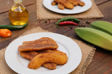 Delicious fried bananas, fresh fruits and different peppers on wooden table