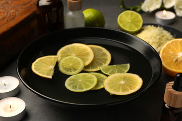 Bowl of essential oil and lemons on grey table. Aromatherapy treatment