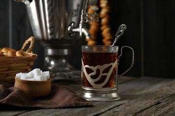 Glass of tea in vintage holder and samovar on wooden table