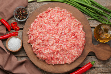 Board with raw fresh minced meat and ingredients on wooden table, flat lay