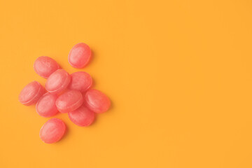 Fototapeta na wymiar Many pink cough drops on orange background, flat lay. Space for text